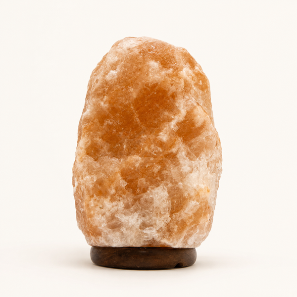 Natural Himalayan pink salt lamp on wooden base against a white background