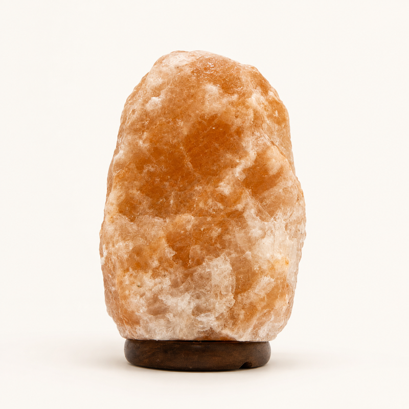 Natural Himalayan pink salt lamp on wooden base against a white background
